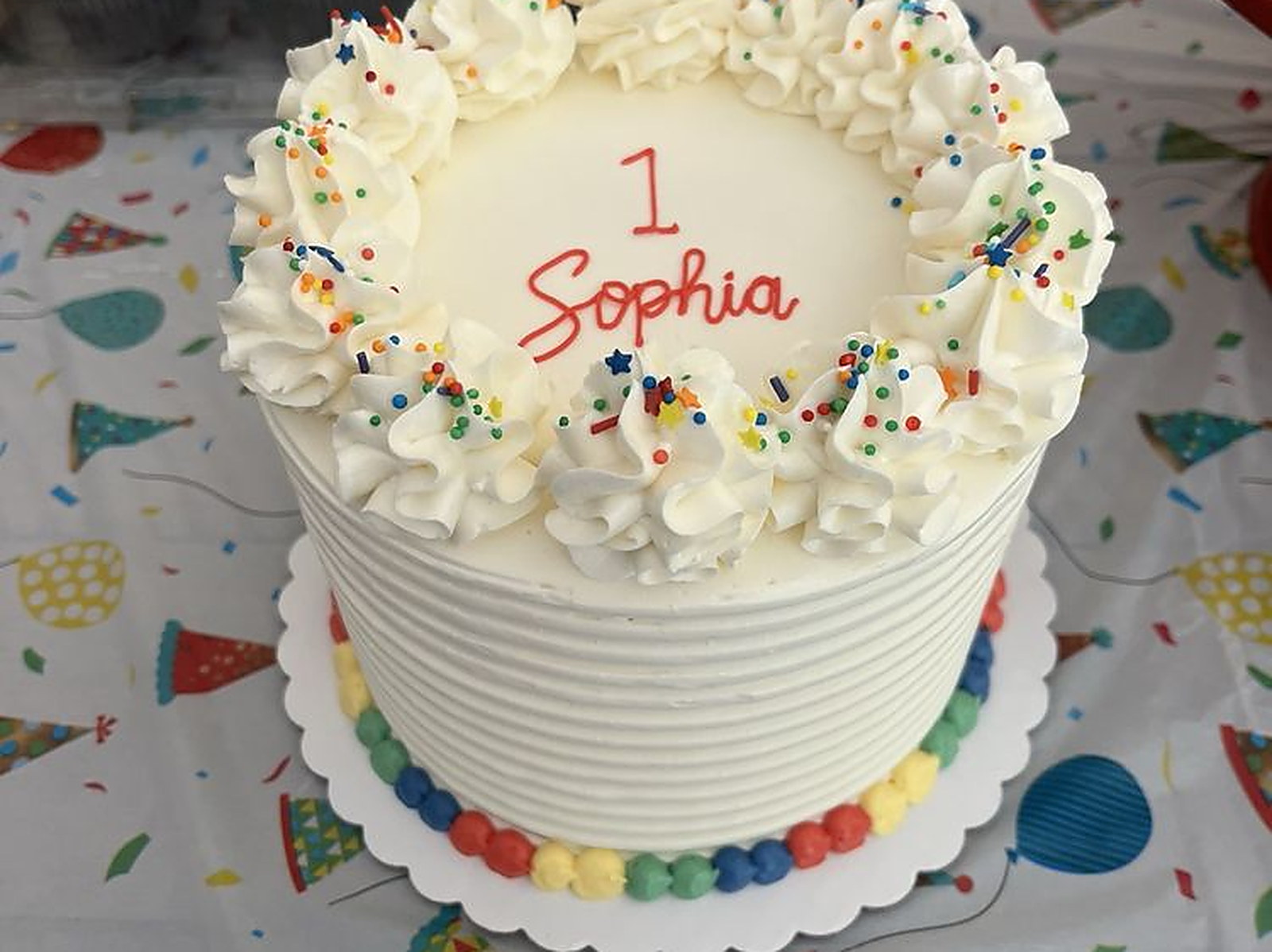 First birthday, her name in red &mdash; custom cake with sprinkle rosettes
